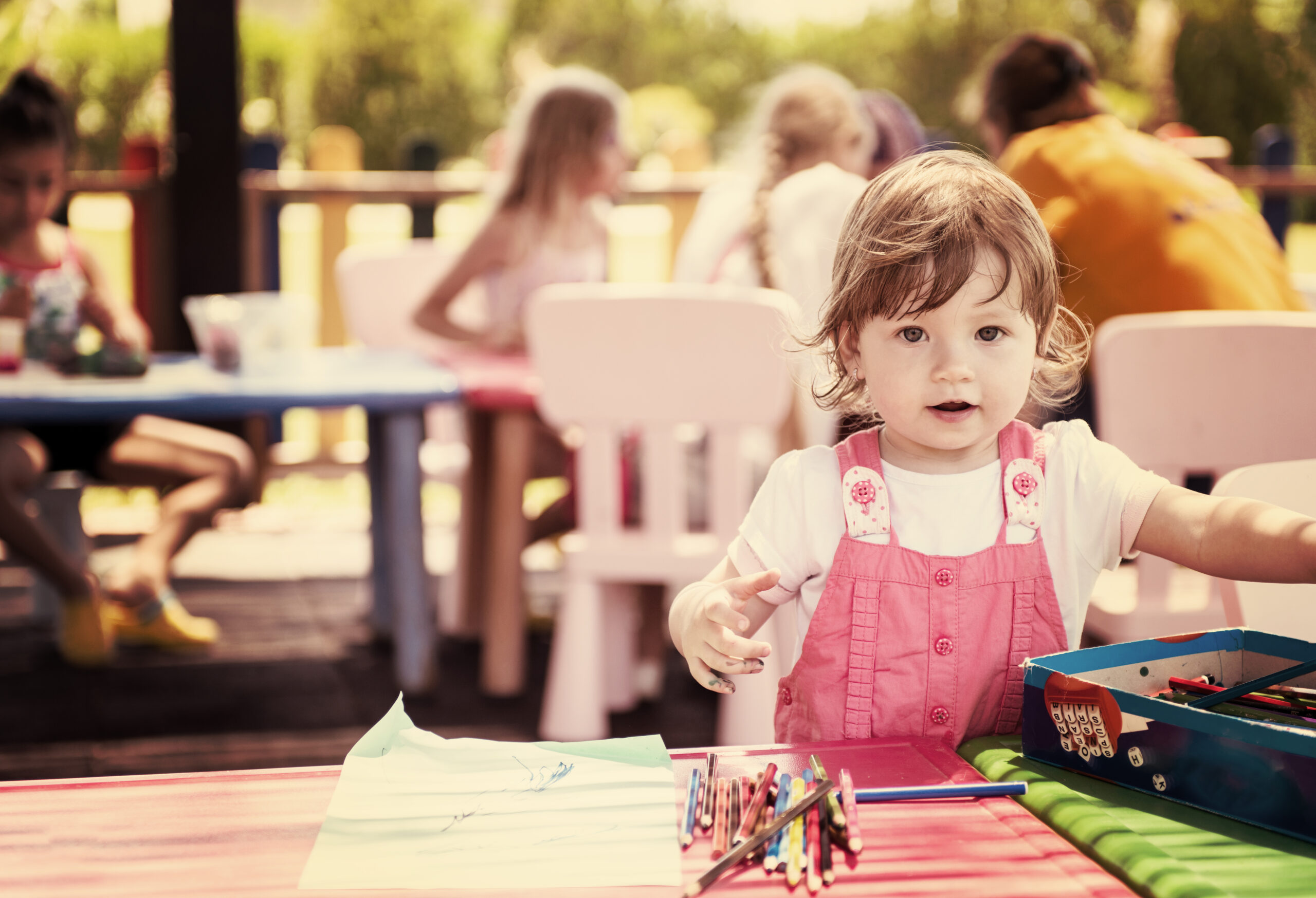 A parent fills out a Tax-Free Childcare application on their laptop while their child plays nearby, showcasing how the program helps families save money and balance work with childcare.